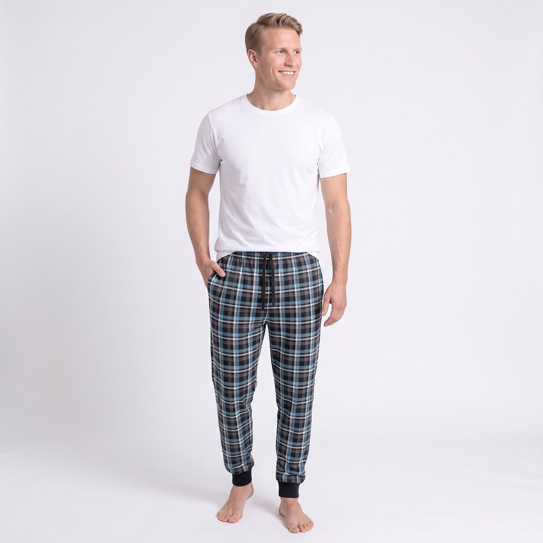 Man i blå- och grårutiga pyjamasbyxor från Gaubert med rymliga ben, elastisk midja och svarta resårmuddar