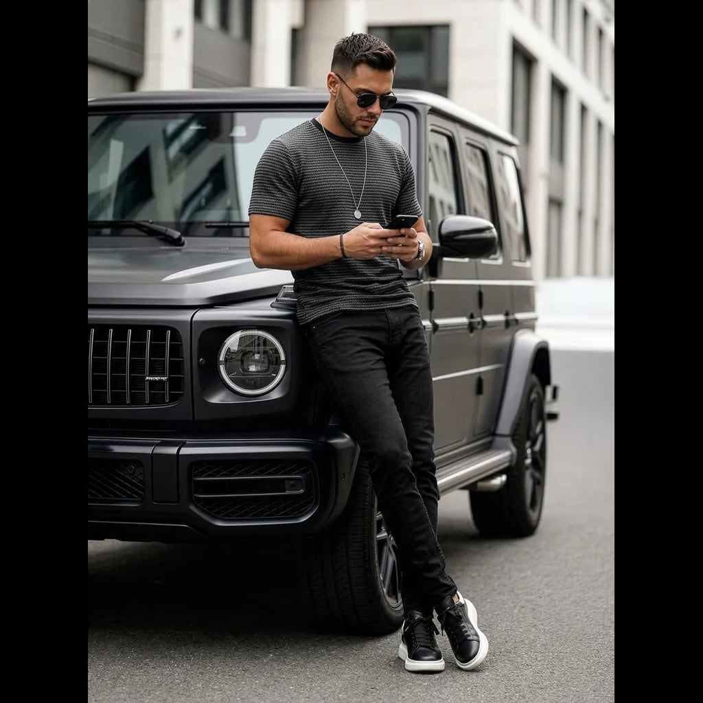 Herrmodell i svart mönstrad t-shirt i bomull matchad med svarta jeans och sneakers, modern outfit