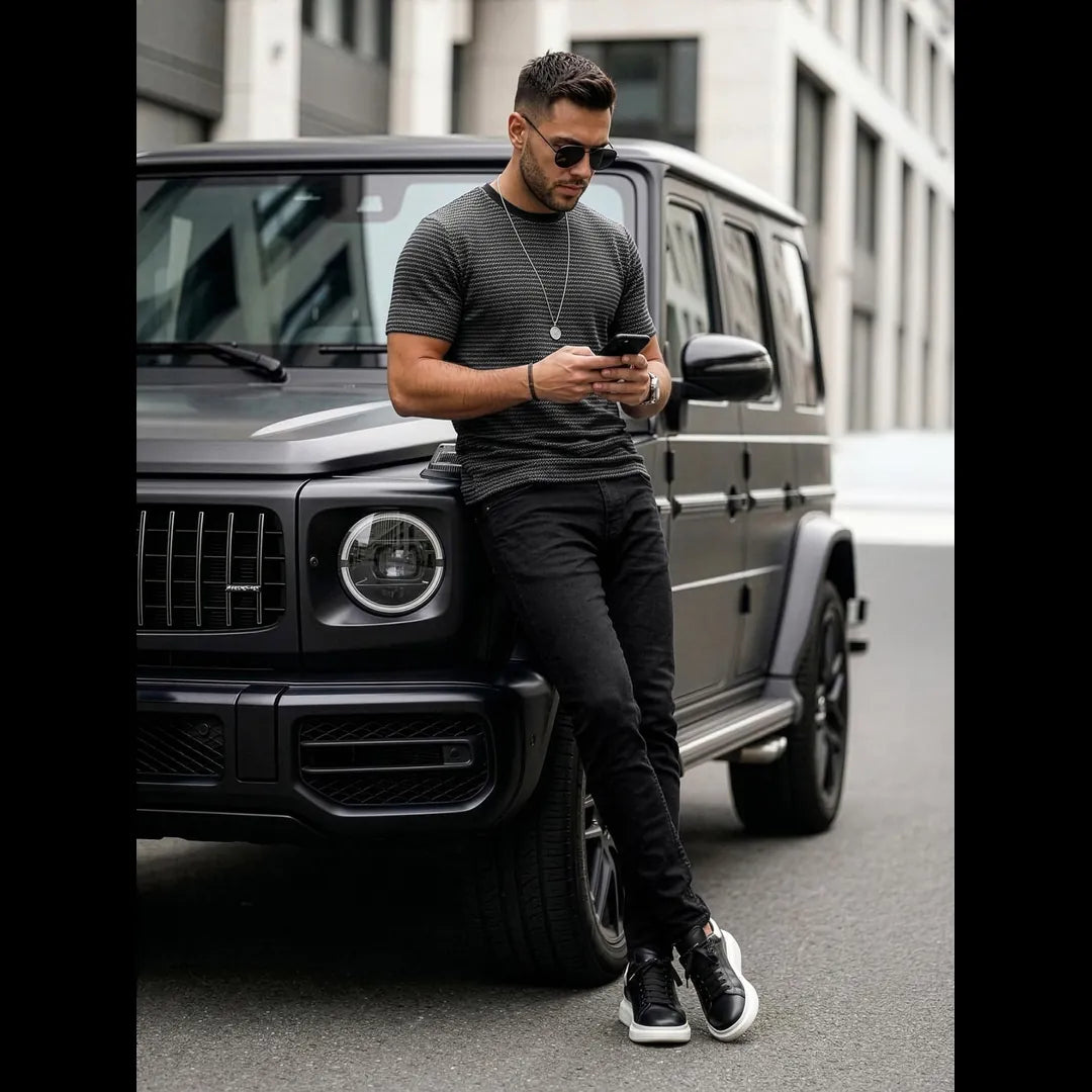 Herrmodell i svart mönstrad t-shirt i bomull matchad med svarta jeans och sneakers, modern outfit