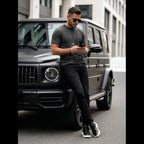 Herrmodell i svart mönstrad t-shirt i bomull matchad med svarta jeans och sneakers, modern outfit