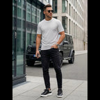 Herrmodell i vit mönstrad t-shirt i bomull matchad med svarta jeans och sneakers, modern outfit