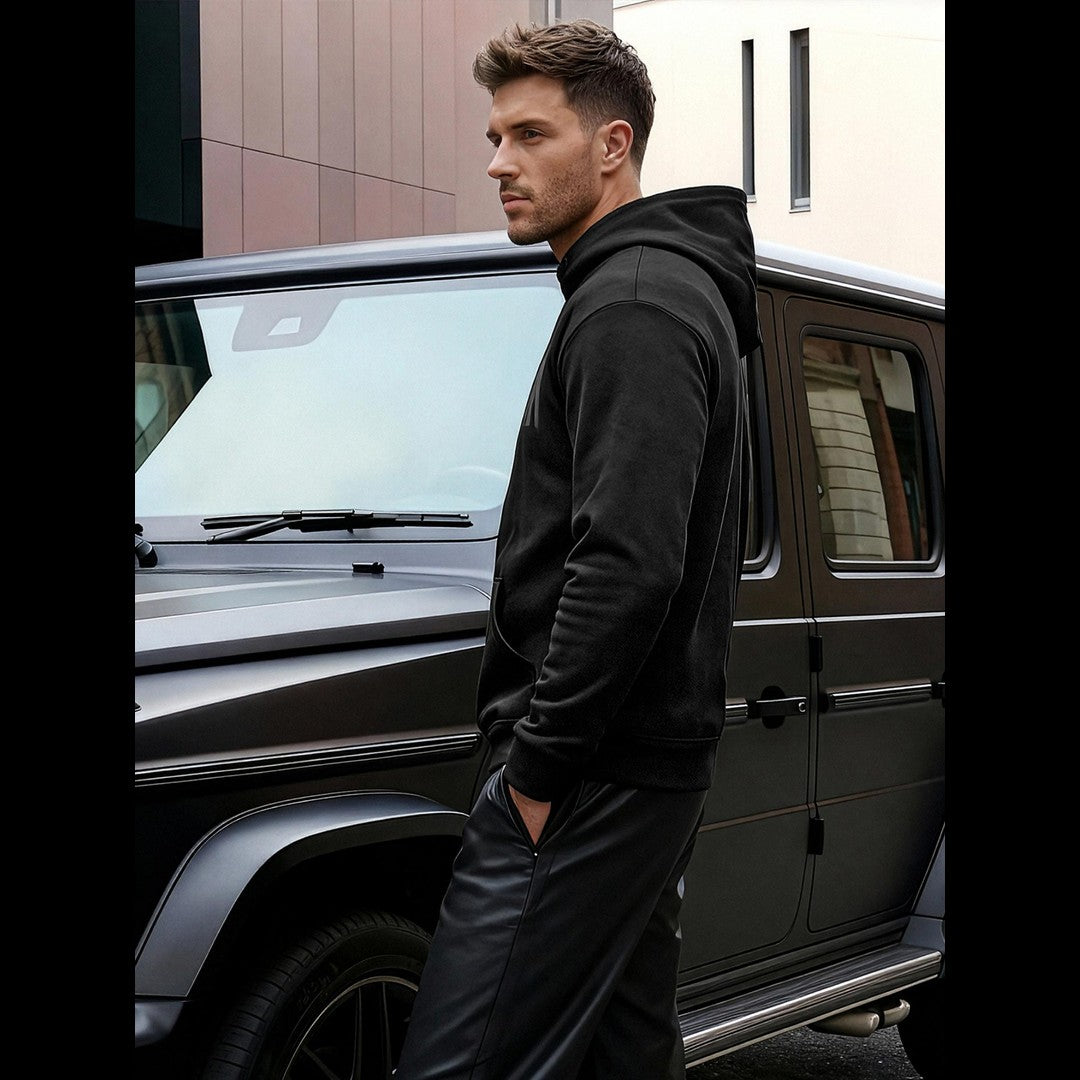 Svart Urban hoodie herr från sidan framför bil – modern streetwear från sidan