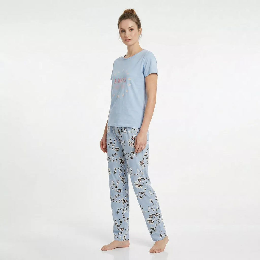 Dam bär ljusblå kortärmad pyjamas i 100% bomull med blommiga byxor