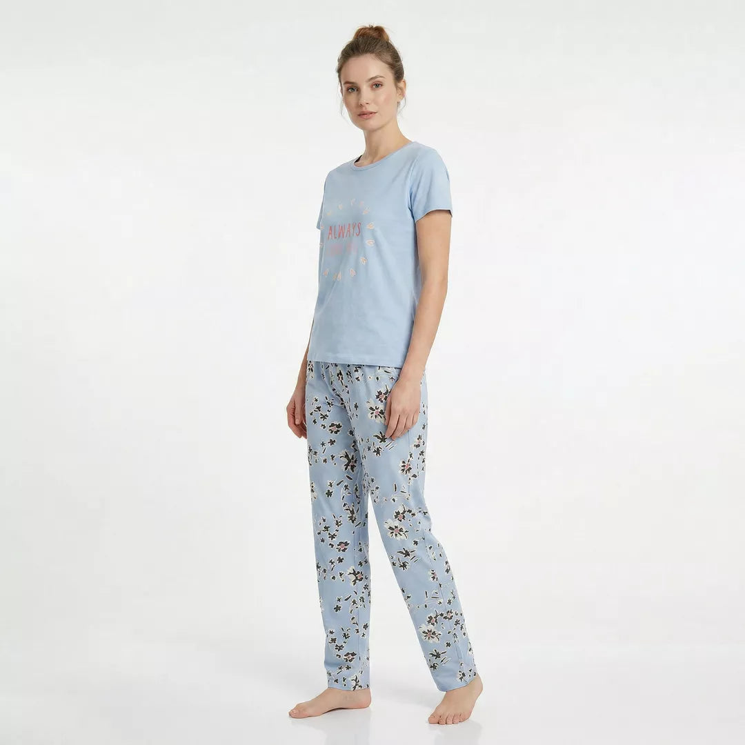 Dam bär ljusblå kortärmad pyjamas i 100% bomull med blommiga byxor