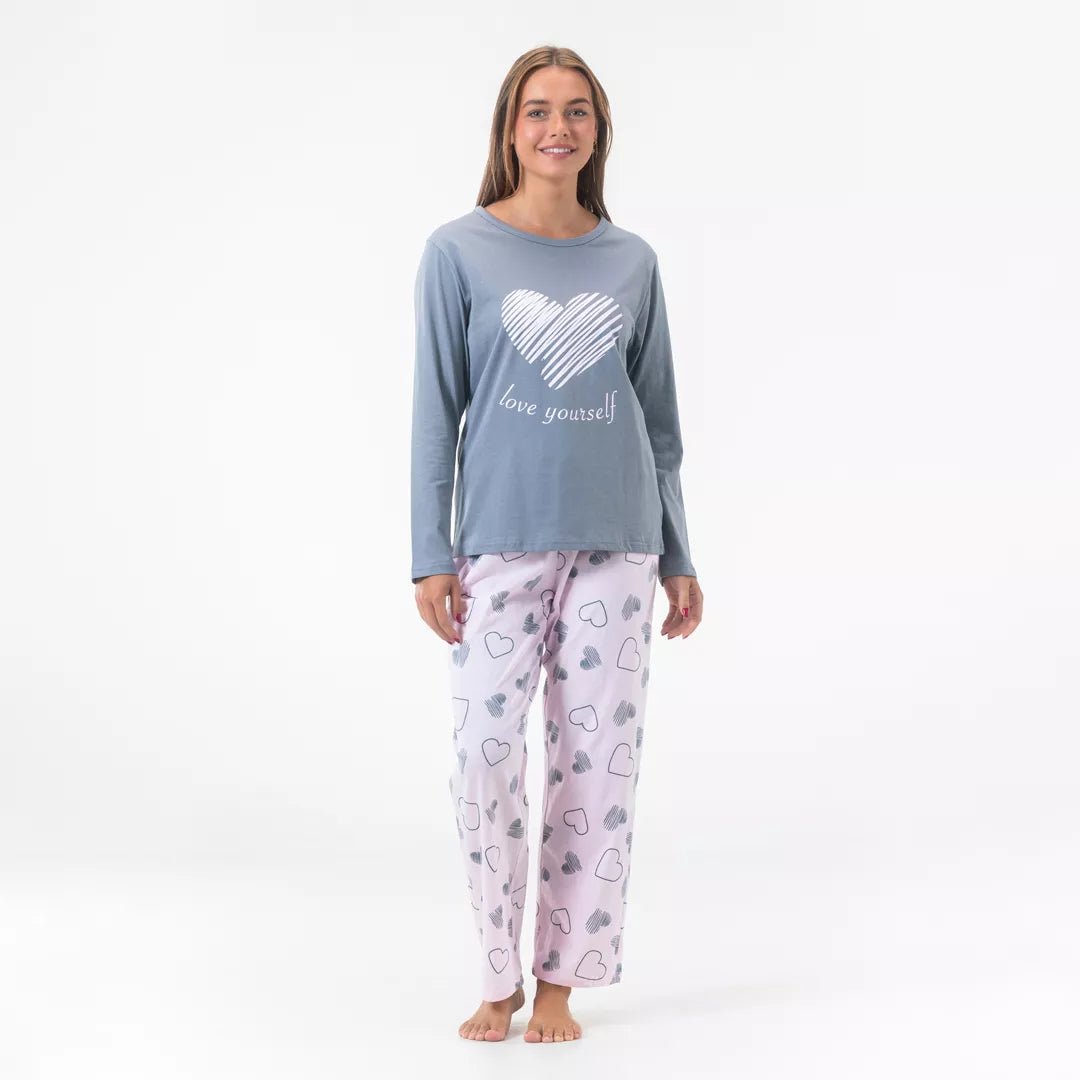 Kvinnlig modell bär Gaubert® pyjamas i 100% bomull med långärmad tröja och hjärtmönstrade byxor.